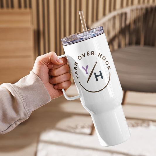 White 40 oz Yarn Over Hook travel mug with handle and straw held in a cozy indoor setting