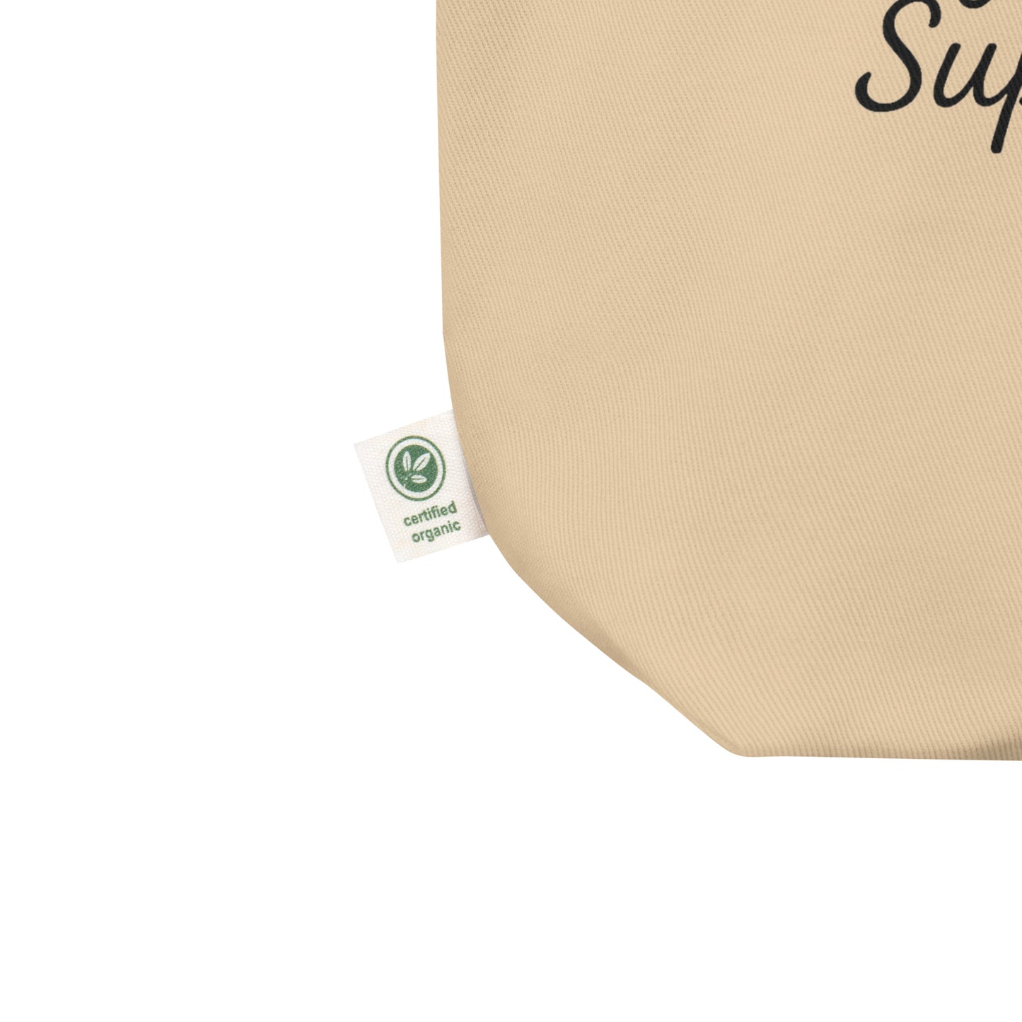 Close-up of the bottom corner of the Oyster-colored organic cotton tote bag showing the green “certified organic” fabric tag.