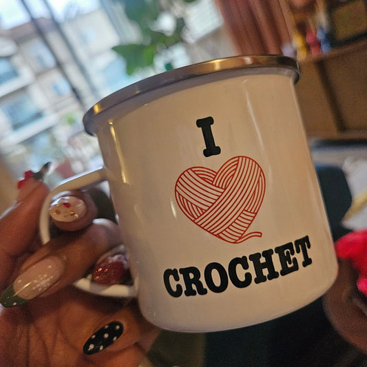 Mug with 'I ❤️ CROCHET' text held by a hand in a casual setting.