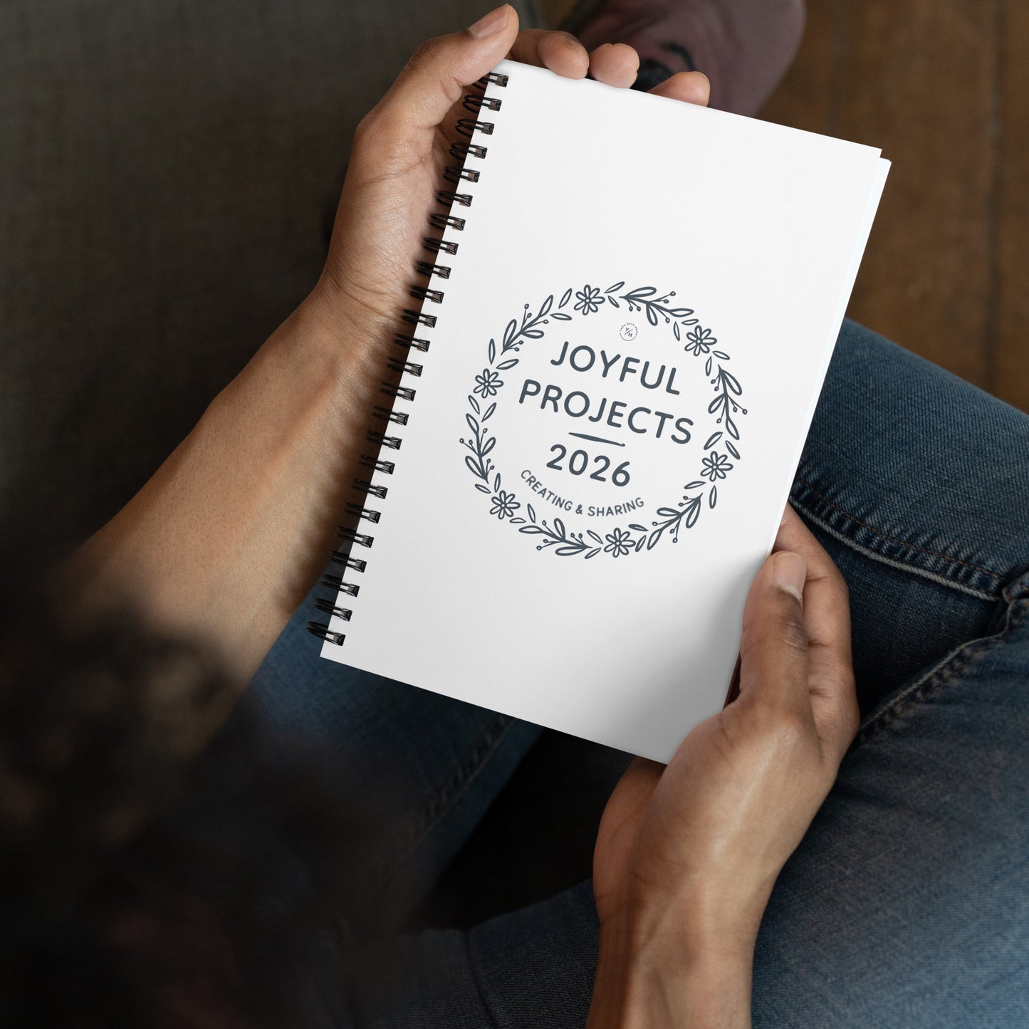 Spiral notebook with floral wreath design reading “Joyful Projects 2026 – Creating & Sharing.”