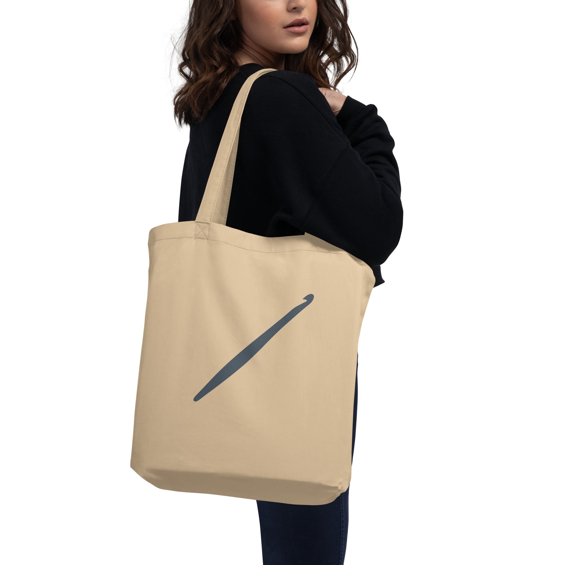 Person carrying an oyster Yarn Over Hook organic cotton tote bag with slate Crochet Community logo.